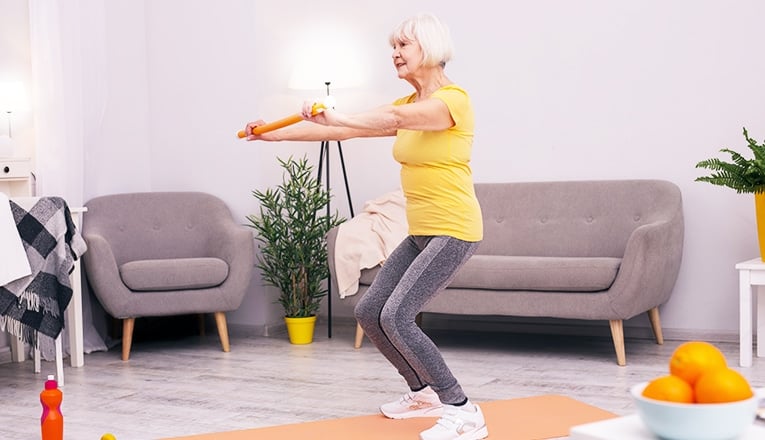 Een oudere vrouw doet squats als fitness oefening.